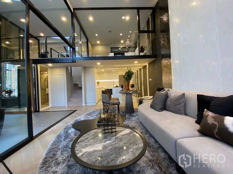 独立式住宅 出售在Watthana, Bangkok - 宽阔客厅，大沙发与嵌套茶几，玻璃围合夹层
