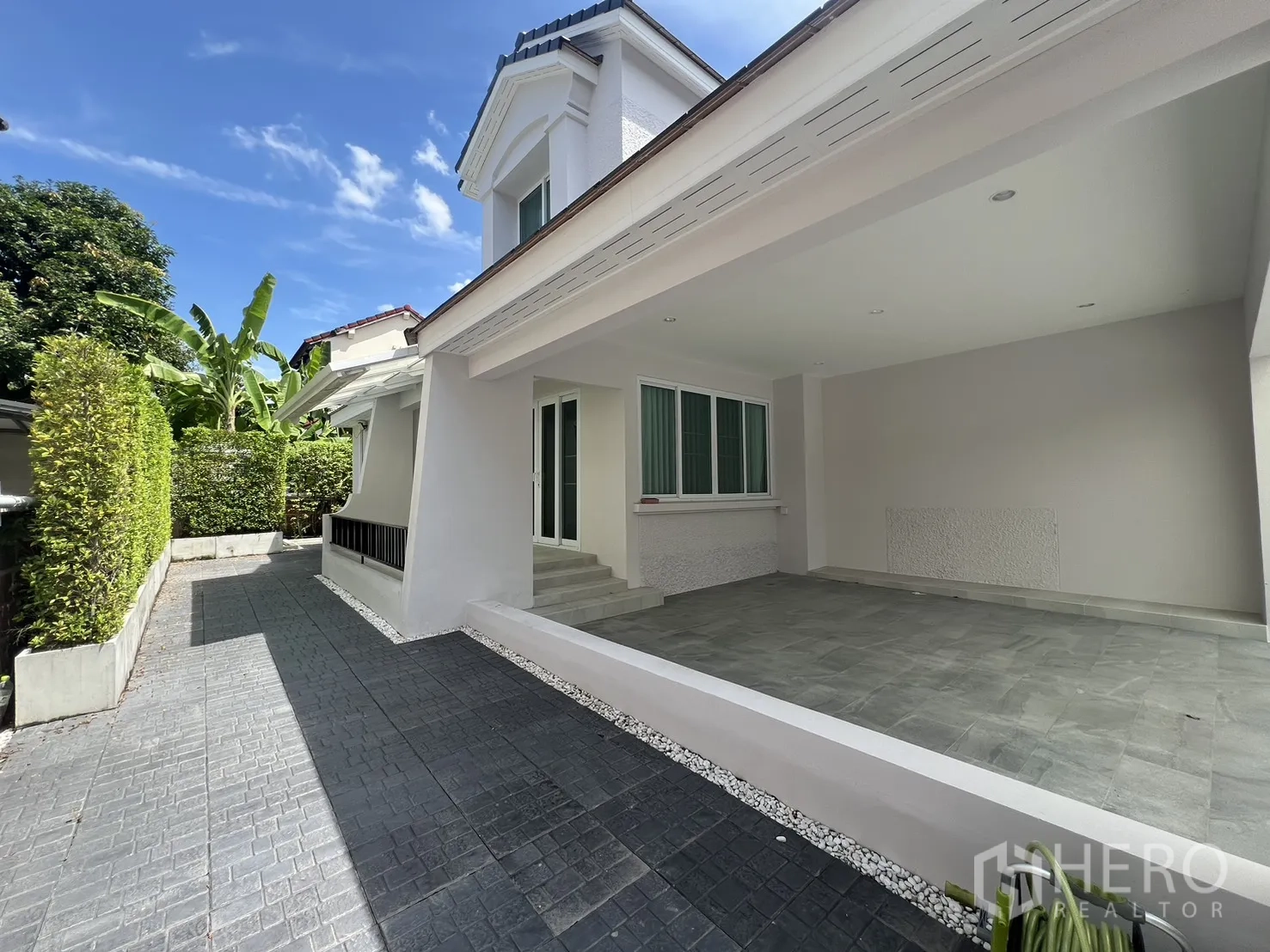 Detached House for rent in Mueang Samut Prakan, Samut Prakan - Covered carport and side walkway bordered by privacy hedges.