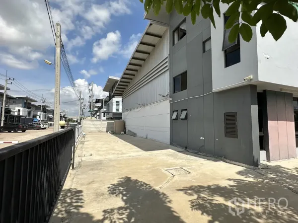 Factory for rent or sale in Pathum Thani - Driveway beside factory within a tidy industrial estate with neighboring units.