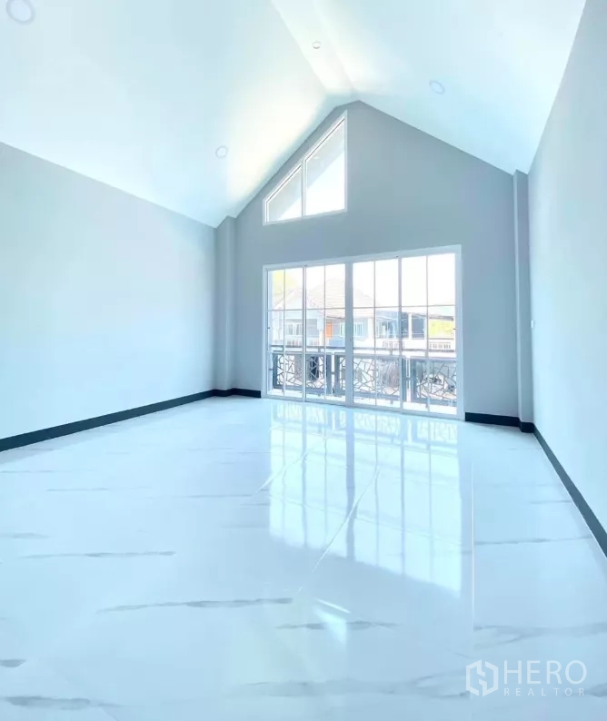 Factory for rent or sale in Bang Bua Thong, Nonthaburi - Upper living area with vaulted ceiling and balcony sliding doors.
