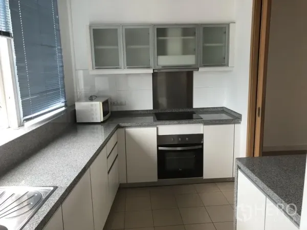 Condominium for rent in Khlong Toei, Bangkok - Enclosed modern kitchen with L-shaped granite counters, glass-front cabinets and built-in oven.