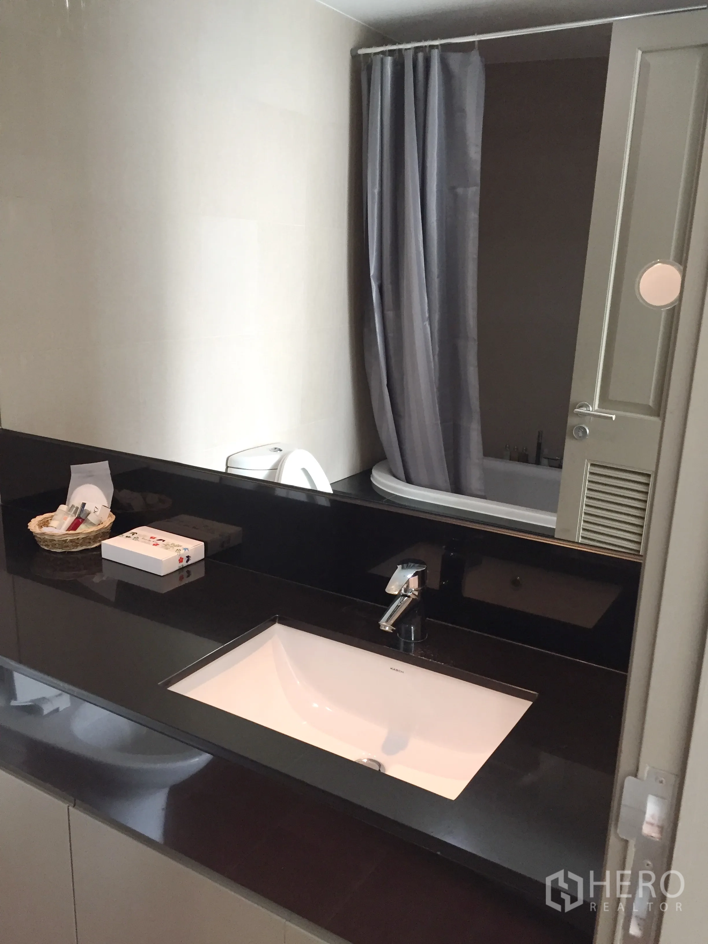 คอนโด ให้เช่าในPathum Wan, Bangkok - ห้องน้ำสมัยใหม่ เคาน์เตอร์สีดำ อ่างล้างหน้า กระจก และอ่างอาบน้ำพร้อมผ้าม่าน