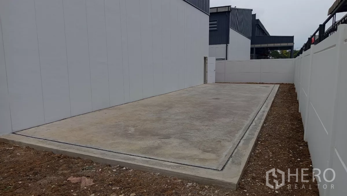 Warehouse for rent or sale in Lam Luk Ka, Pathum Thani - Private concrete loading yard and driveway beside the warehouse.