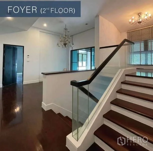 Detached House for sale in Khlong Toei, Bangkok - Second-floor foyer with wood staircase, glass railing and chandelier.