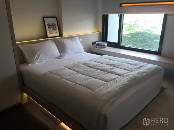 คอนโด ให้เช่าในWatthana, Bangkok - ห้องนอนสว่าง เตียงฐานไม้ ไฟซ่อน และหน้าต่างบานใหญ่เห็นวิวต้นไม้