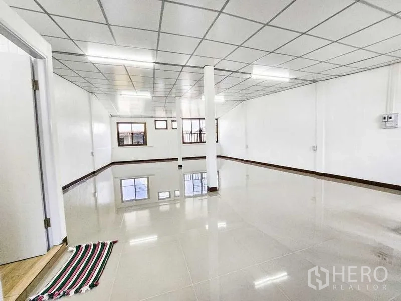 Home Office for rent in Khlong Toei, Bangkok - Sunlit upper room with grid ceiling, multiple windows and reflective porcelain tiles.