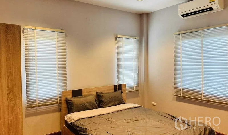 Detached House for rent in Lam Luk Ka, Pathum Thani - Guest bedroom with wooden bed, three windows and air conditioning.