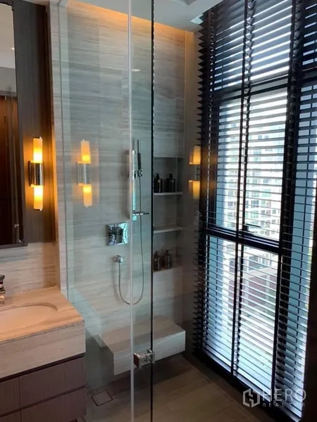 Condominium for rent in Bang Rak, Bangkok - Modern bathroom featuring a glass shower, wall niches, large window with blinds, and marble vanity.