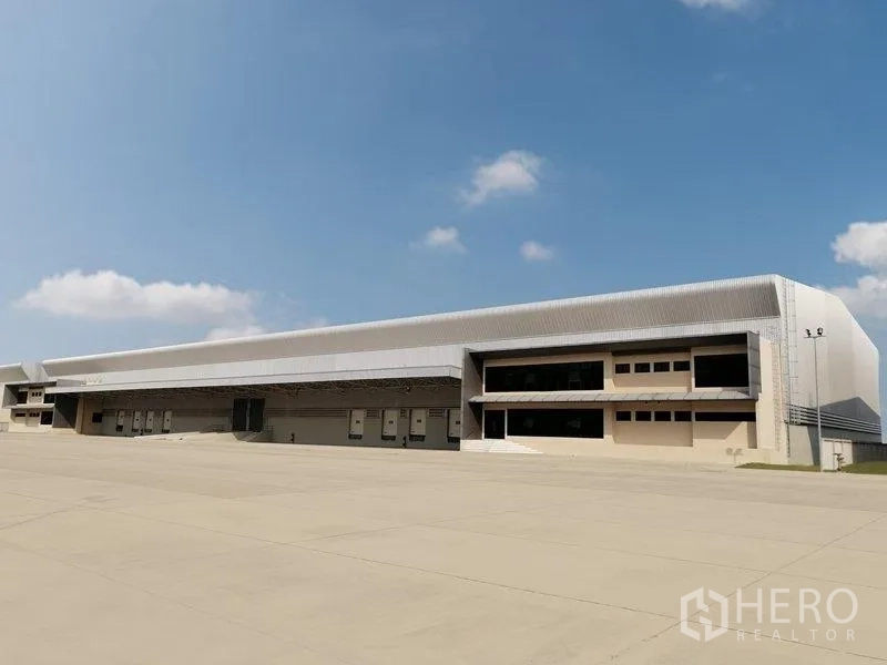 Factory for rent in Bang Pakong, Chachoengsao - Modern factory exterior in Bang Pakong, Chachoengsao with multiple loading docks and a vast concrete yard.