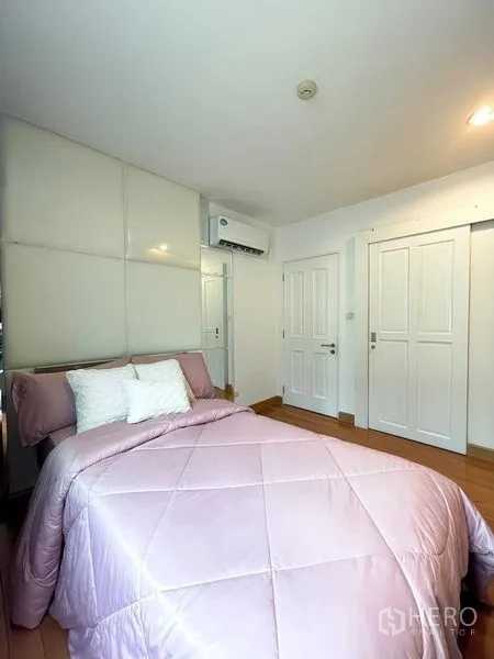 Condominium for rent - Second bedroom with pink bedding, white wardrobes and air conditioning.