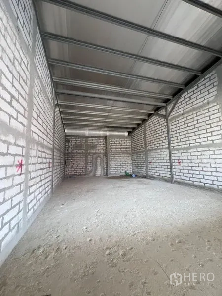 Retail Space for rent in Khlong Toei, Bangkok - Interior view of unfinished retail space showing metal roof trusses, bare floor, and brick walls.