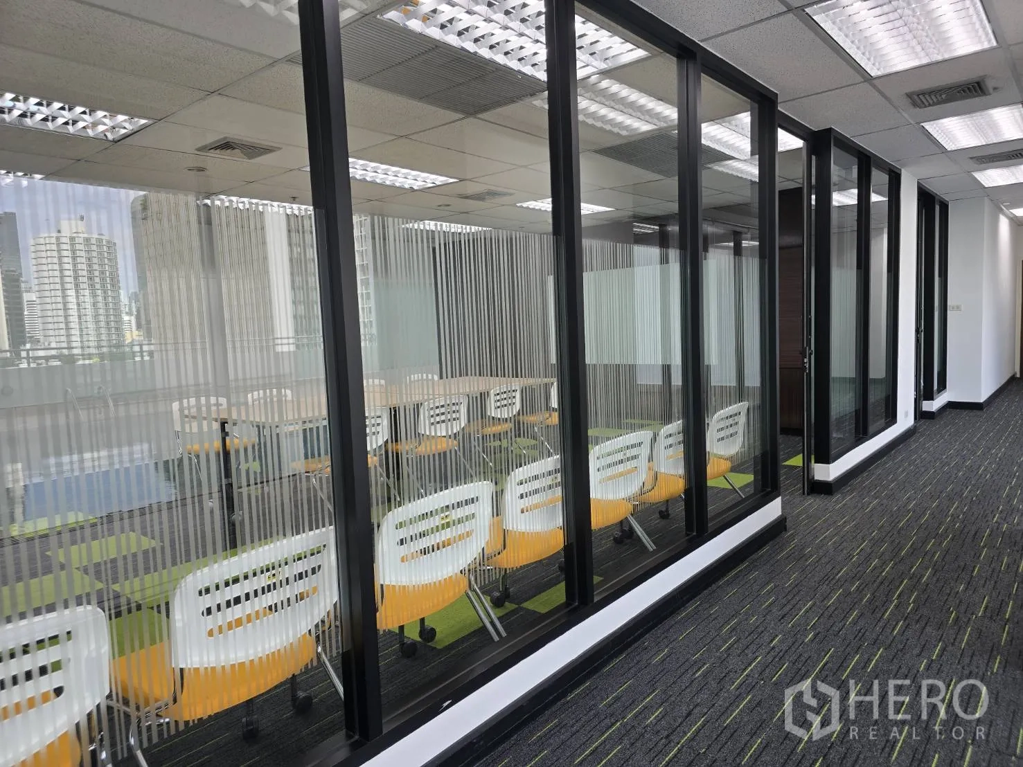 ออฟฟิศ for rent in Watthana, Bangkok - ห้องกั้นกระจกพร้อมแถวเก้าอี้และเงาสะท้อนตึกเมืองบนกระจก.