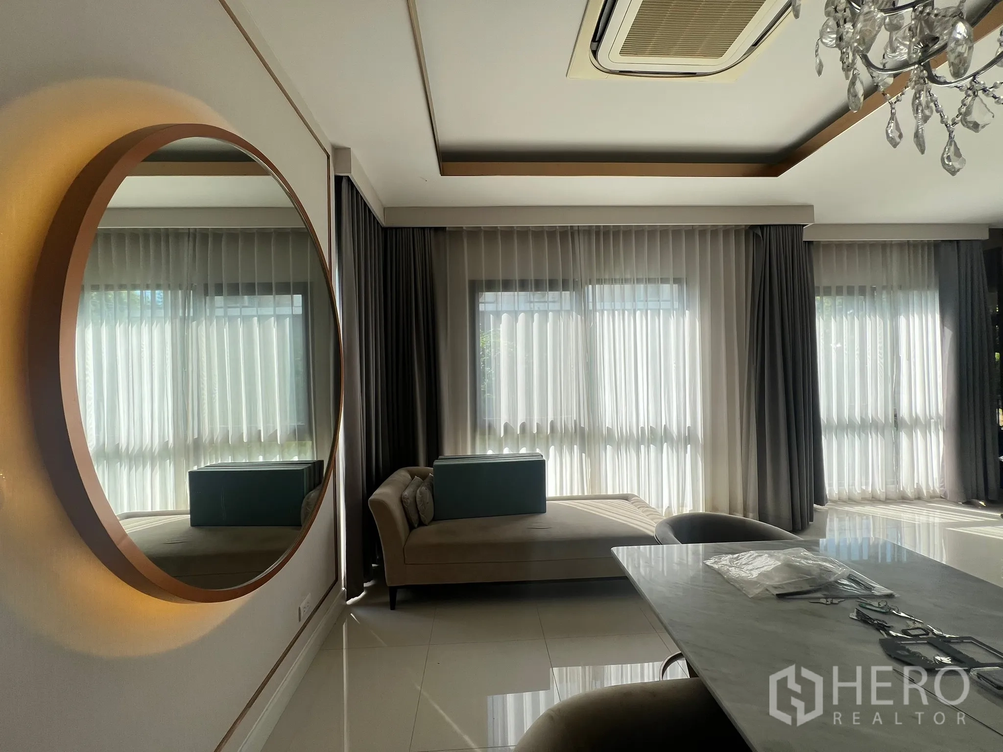 Detached House for rent or sale in Prawet, Bangkok - Corner lounge with a backlit round mirror, chaise and sheer curtains.
