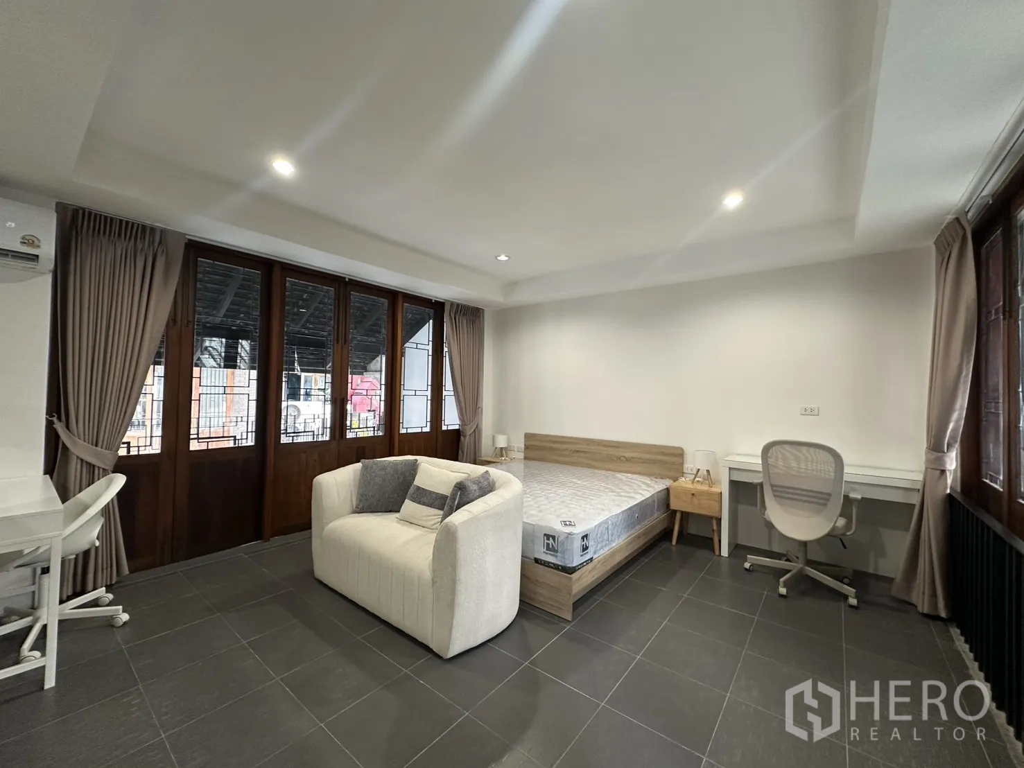 公寓 for rent in Pathum Wan, Bangkok - 卧室通向阳台，内有床、书桌与躺椅。