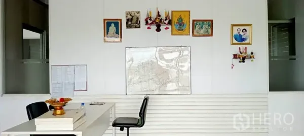 Warehouse for rent or sale in Lam Luk Ka, Pathum Thani - Simple office wall inside the warehouse with desk, chairs, and framed decorations.