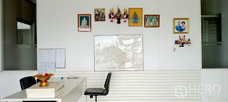 Warehouse for rent or sale in Lam Luk Ka, Pathum Thani - Simple office wall inside the warehouse with desk, chairs, and framed decorations.