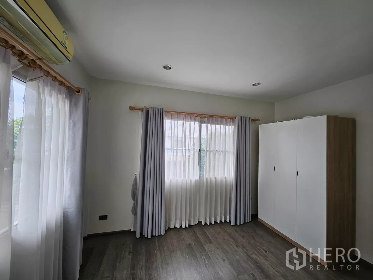 Detached House for rent in Khlong Toei, Bangkok - Guest bedroom with large windows, freestanding wardrobe and sheer curtains.