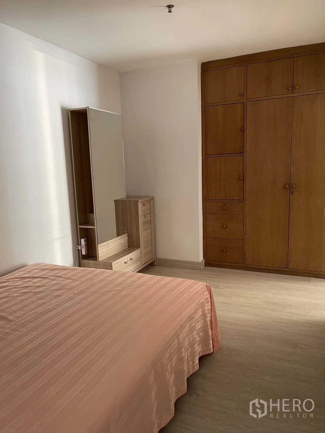 Condominium for rent or sale in Watthana, Bangkok - Bedroom featuring built-in wooden wardrobes and a dressing table.