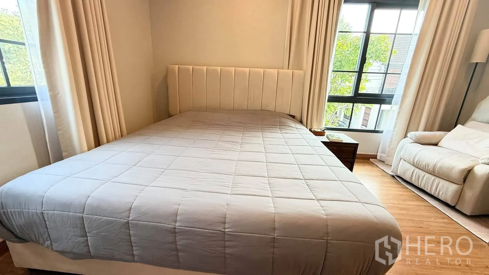 บ้านเดี่ยว for rent in Bang Phli, Samut Prakan - ห้องนอนมาสเตอร์หัวเตียงบุผ้าสูง มองเห็นวิวต้นไม้ผ่านหน้าต่างกว้าง