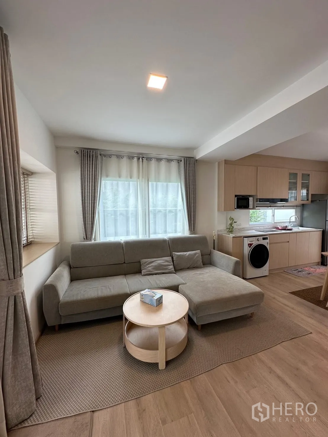 Townhouse for rent in Prawet, Bangkok - Open-plan living area with L-shaped sofa next to the fitted kitchen.