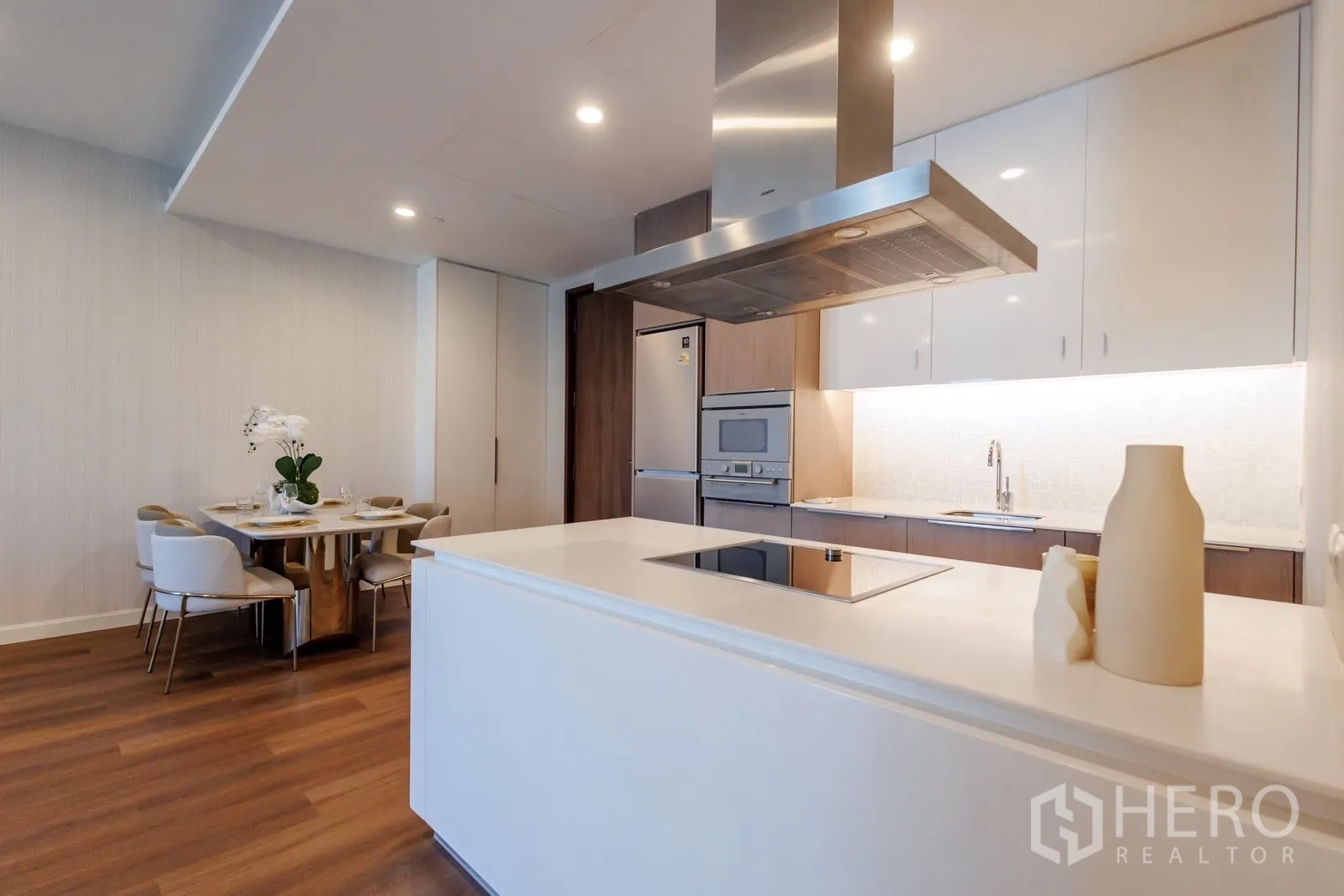 คอนโด for rent or sale in Pathum Wan, Bangkok - ครัวแบบเปิดพร้อมไอส์แลนด์ เครื่องใช้บิวท์อิน และชุดโต๊ะทานอาหาร