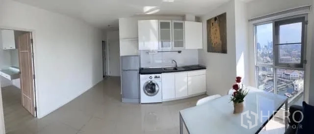 Condominium for sale in Khlong Toei, Bangkok - Open kitchen with white cabinets, sink and washing machine beside dining area.