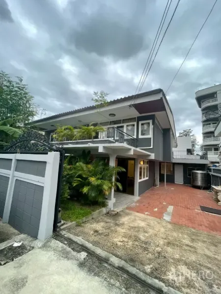独立式住宅 出租在Watthana, Bangkok - 灰色双层独栋别墅外观，带大门入口、红砖车道与葱郁绿植。