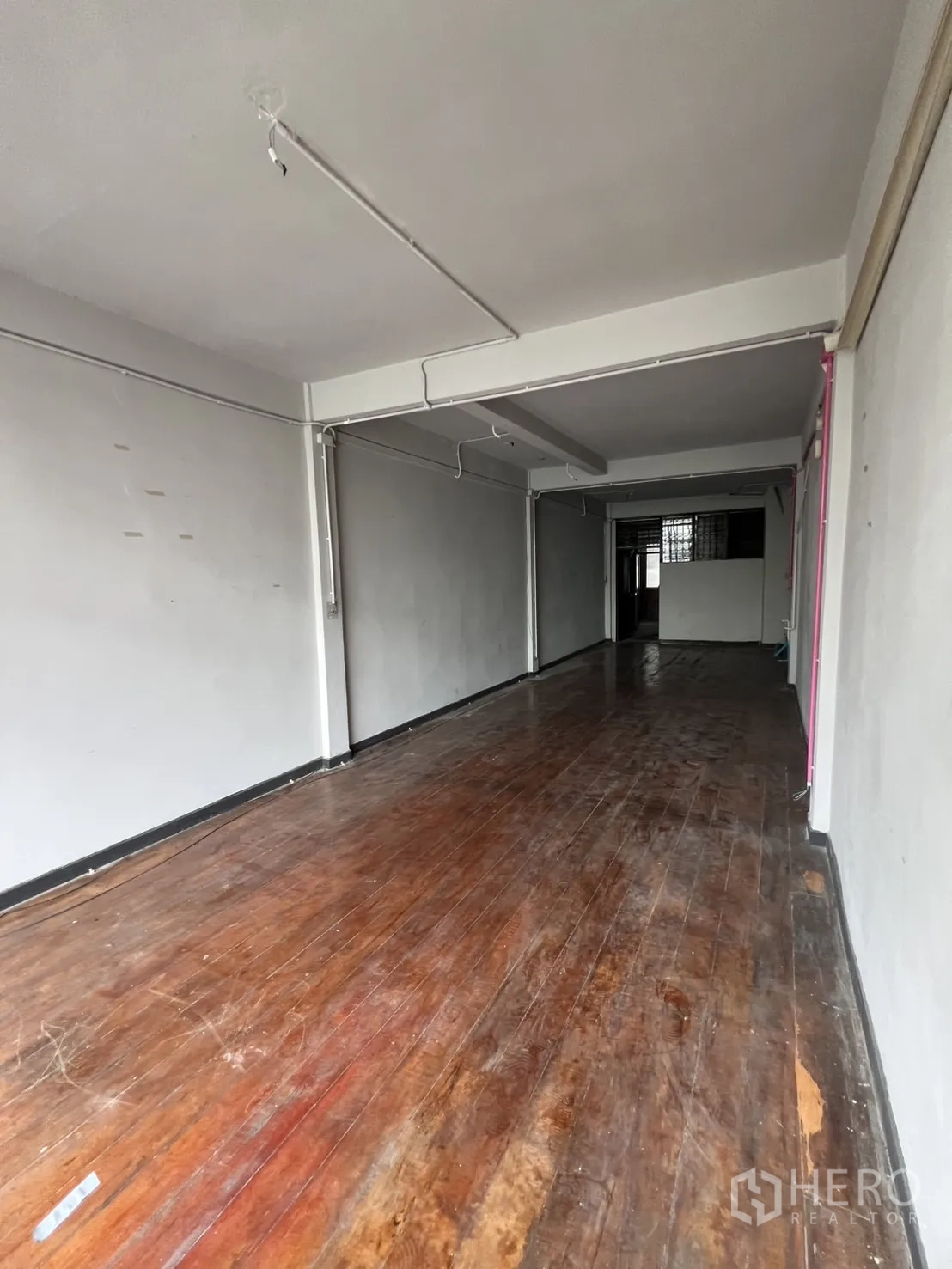 Shophouse for rent in Watthana, Bangkok - Upper-floor open room with polished wooden flooring and white walls.