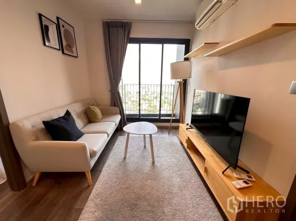 公寓 出租在Chatuchak, Bangkok - 客厅明亮，奶油色沙发、电视柜与阳台，位于Life Ladprao Valley。