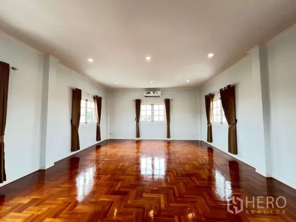 Detached House for rent in Bang Phli, Samut Prakan - Expansive multipurpose room with glossy herringbone wood flooring and windows on three sides.