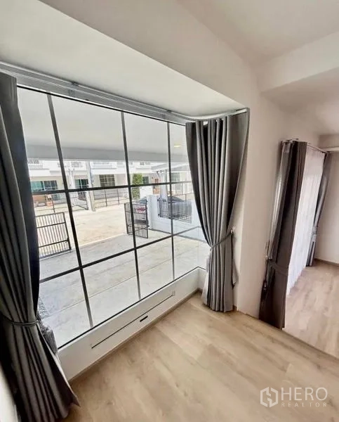 Townhouse for rent in Bang Phli, Samut Prakan - Corner bay window with grey curtains overlooking the driveway and front gate.