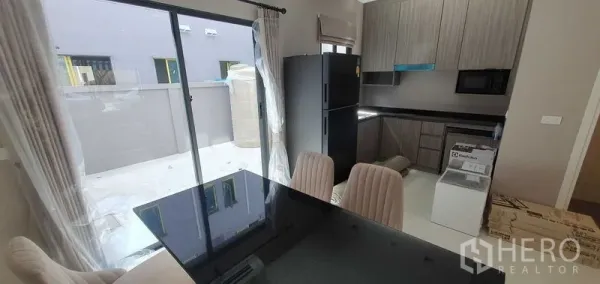 带办公室的家 出租在Prawet, Bangkok - 灰色橱柜与黑色台面的现代厨房，餐桌旁接通露台的推拉门。