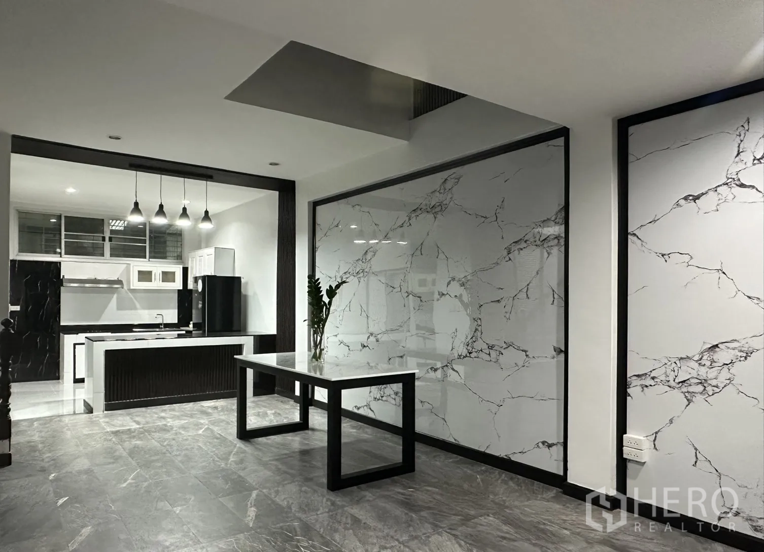 Home Office for rent in Khlong Toei, Bangkok - Open-plan space leading to a modern kitchen with marble-look walls and a table.