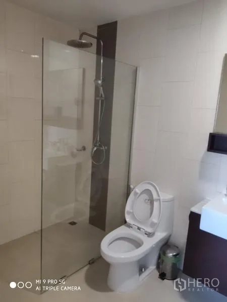 公寓 出租或出售在Pathum Wan, Bangkok - 现代浴室，玻璃隔断雨淋花洒，白色瓷砖，盥洗台与马桶