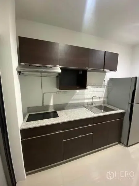 Detached House for rent or sale in Saphan Sung, Bangkok - Compact kitchen with dark cabinets, granite countertop, hob and stainless sink.