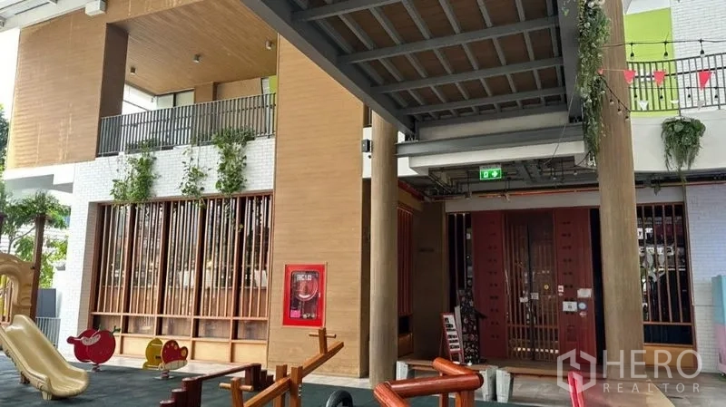 零售空间 出租 - 带顶走道与木质装饰入口，垂挂绿植，旁设儿童游乐区
