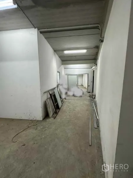 Home Office for rent in Bang Khen, Nonthaburi - Service corridor with white partitions and concrete floor leading to rooms.