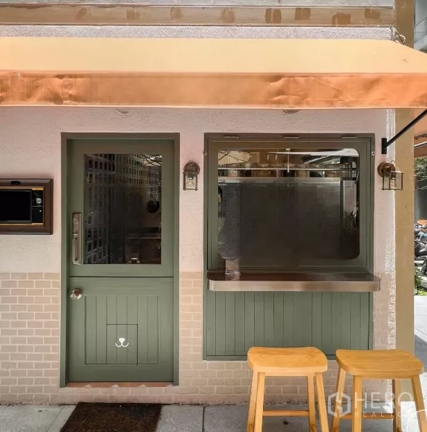 Retail Space for rent in Bang Rak, Bangkok - Shopfront with sage-green door, service window, stainless counter and wooden stools beneath an awning.