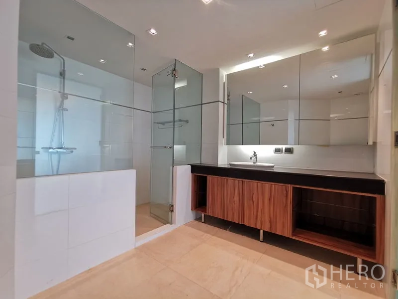 Condominium for rent or sale in Phaya Thai, Bangkok - Modern bathroom with glass-enclosed shower, mirrored cabinets, and wood-grain vanity.