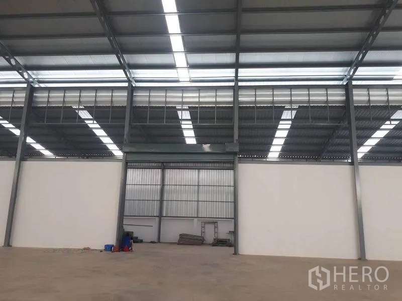 Warehouse for rent in Bang Phli, Samut Prakan - Central bay featuring a large roller shutter door and steel frame structure.