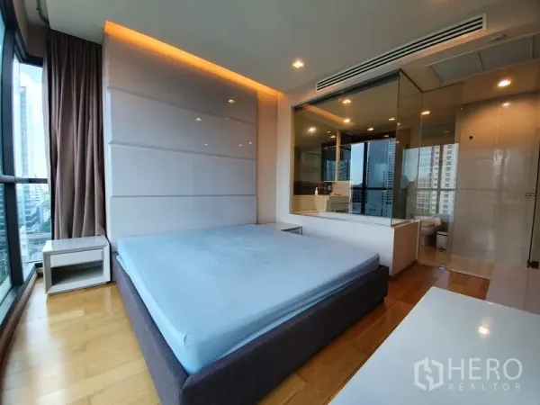 Condominium for rent in Bang Rak, Bangkok - Master bedroom with floor-to-ceiling windows and a glass-walled ensuite bathroom.