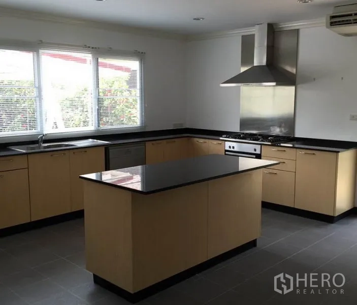 Detached House for rent in Bang Phli, Samut Prakan - Modern U-shaped kitchen with black granite countertops, island, oven, and stainless range hood.
