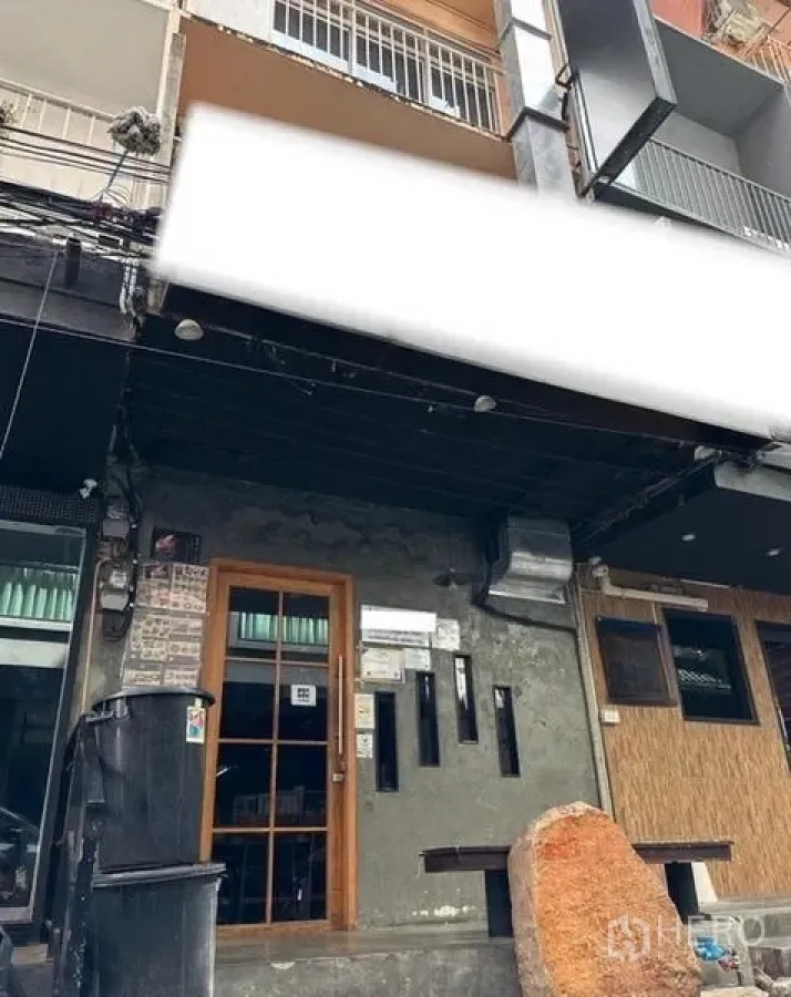 อาคารพาณิชย์ ให้เช่าหรือขายในWatthana, Bangkok - ด้านหน้าตึกแถวติดถนน ซุ้มประตูบานกระจก ผนังคอนกรีต และกันสาดสีดำพร้อมพื้นที่ติดป้าย