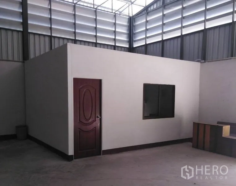 Warehouse for rent in Bang Yai, Nonthaburi - Warehouse interior with a built-in office room featuring a wood door and window under a high ventilated roof.