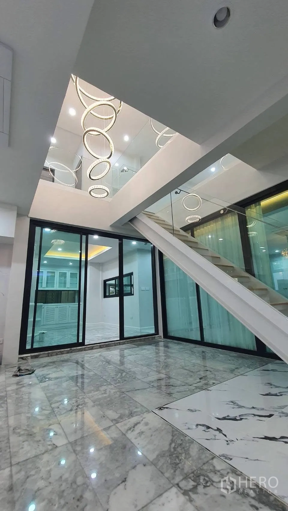 Detached House for rent in Lat Phrao, Bangkok - Glass-walled staircase beside sliding doors and marble flooring.