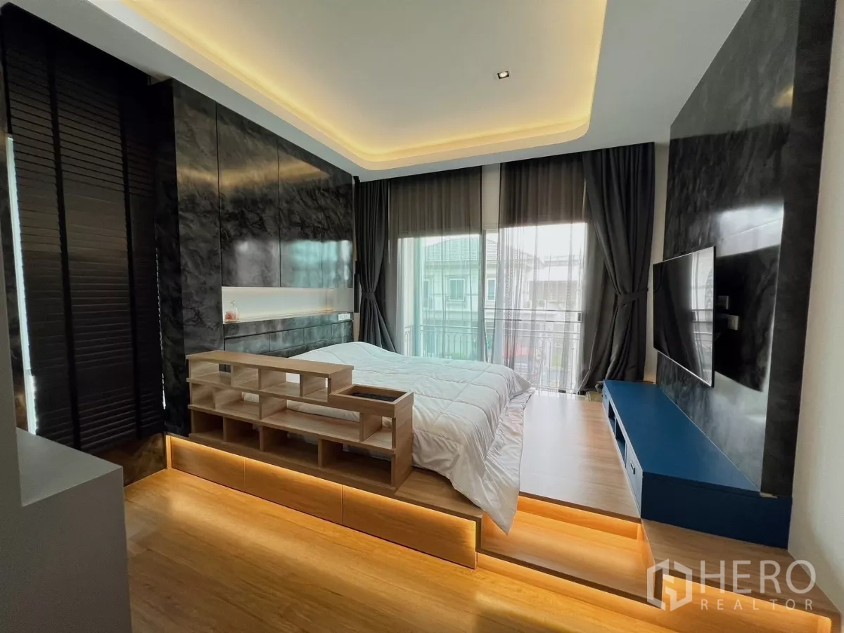 Detached House for rent or sale in Khlong Luang, Pathum Thani - Spacious master bedroom with balcony doors, TV wall and cove lighting.