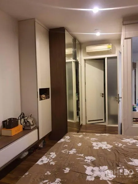 คอนโด ขายในBangkok - มุมห้องนอนมีตู้เสื้อผ้าบานกระจกและประตูเชื่อมไปยังห้องน้ำ