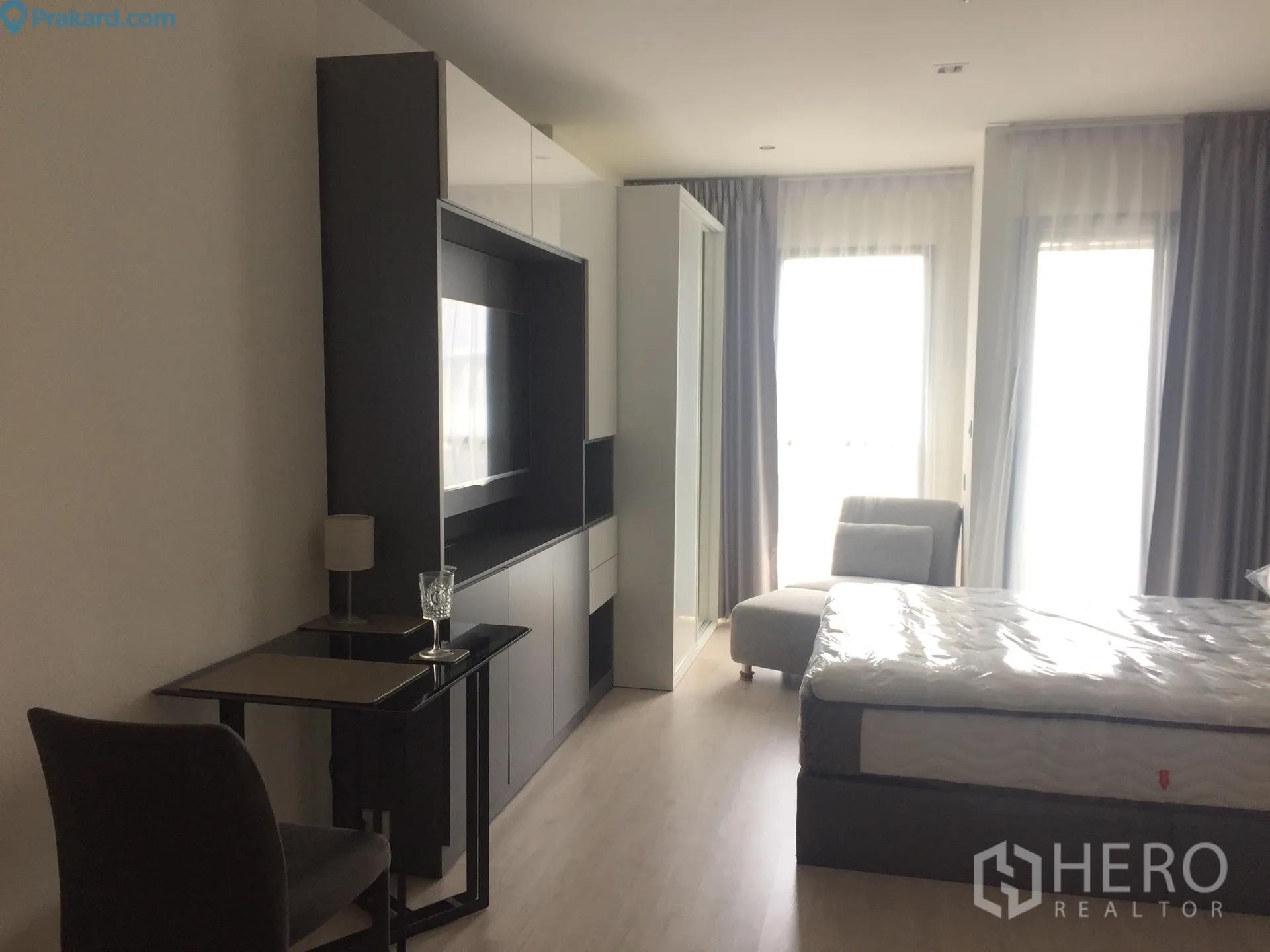 公寓 出租在Ratchathewi, Bangkok - 明亮单间布局，配床、媒体柜、小餐桌与大面积窗帘窗户。