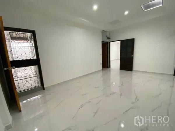 独立式住宅 出租在Huai Khwang, Bangkok - 宽敞客厅，亮面仿大理石地砖与深色木门。