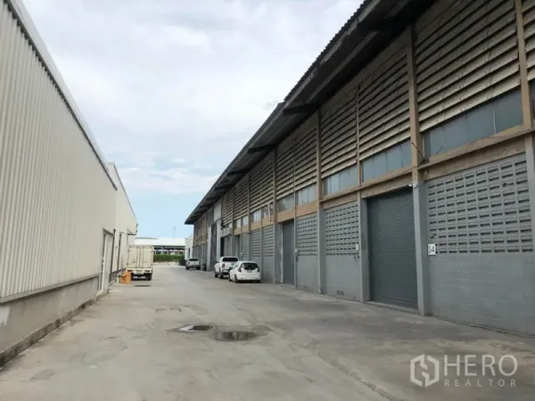 Factory for rent in Mueang Samut Prakan, Samut Prakan - Row of industrial units with roller shutter doors and a wide driveway for truck access.